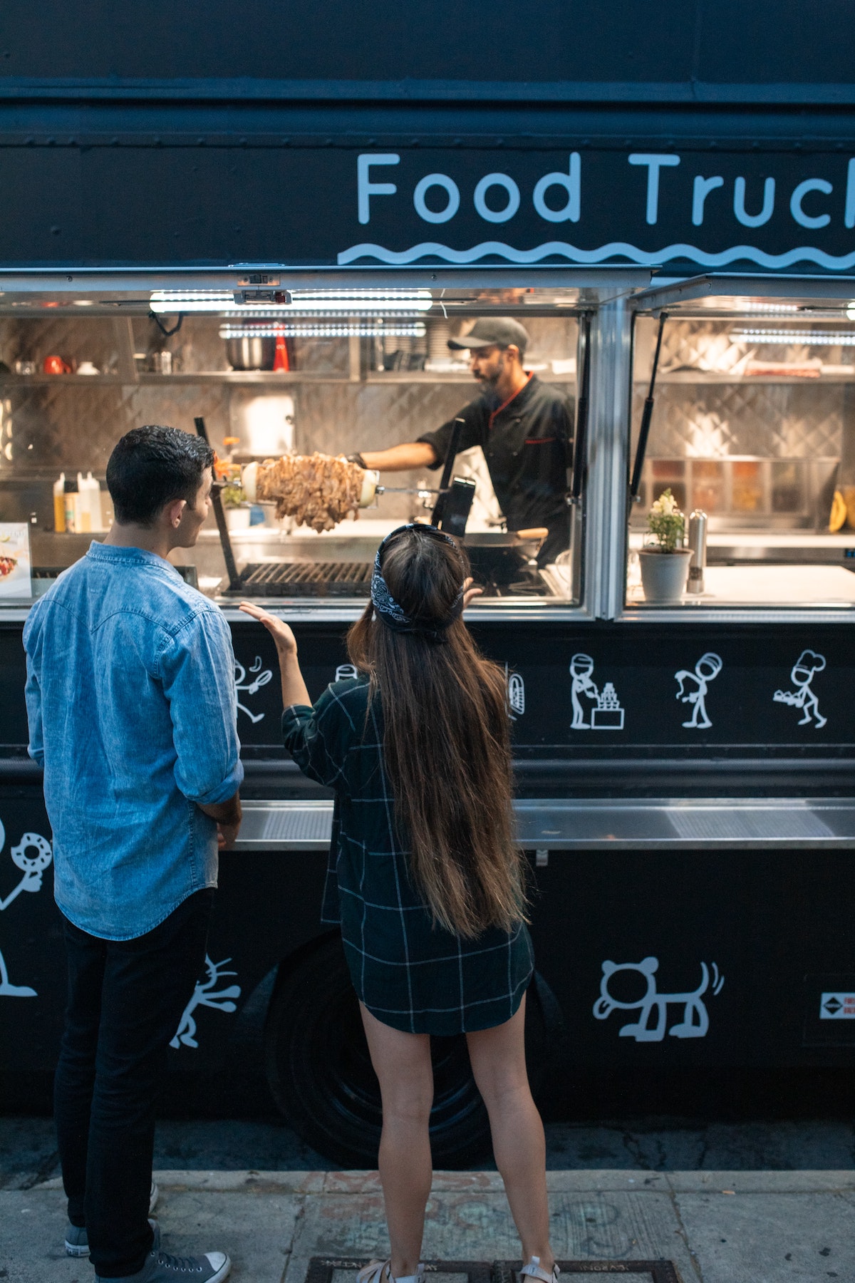 two people stand in front of the order window of a fodo truck