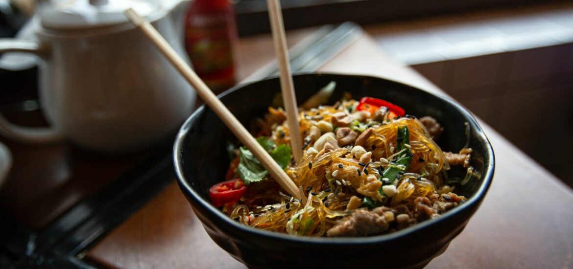 rice noodles in black bowl with chopsticks