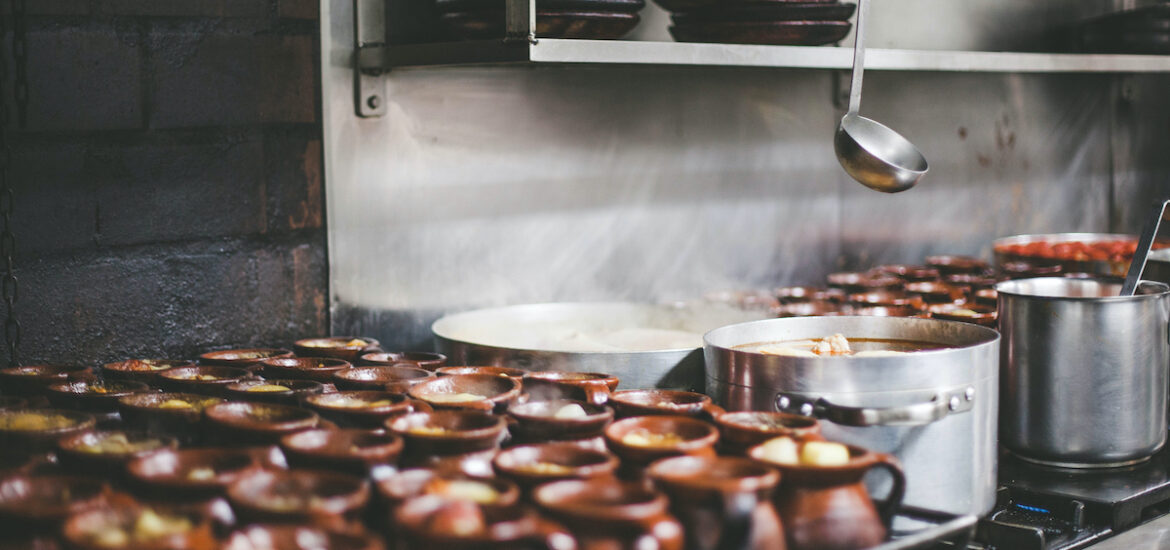 Clay jars and steel pots of stew simmering on a stove.