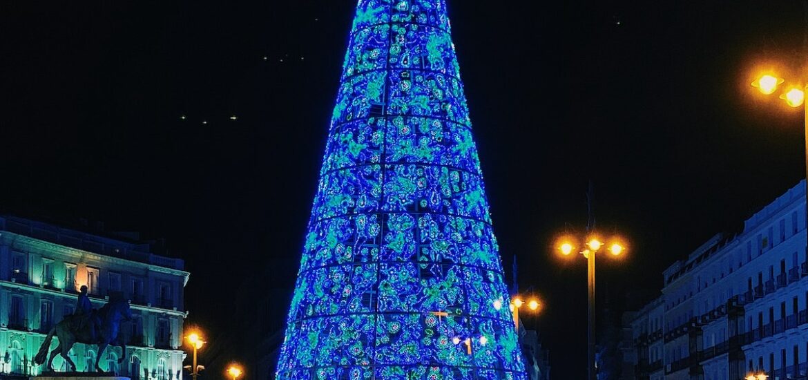 Large blue Christmas tree in a city plaza at night