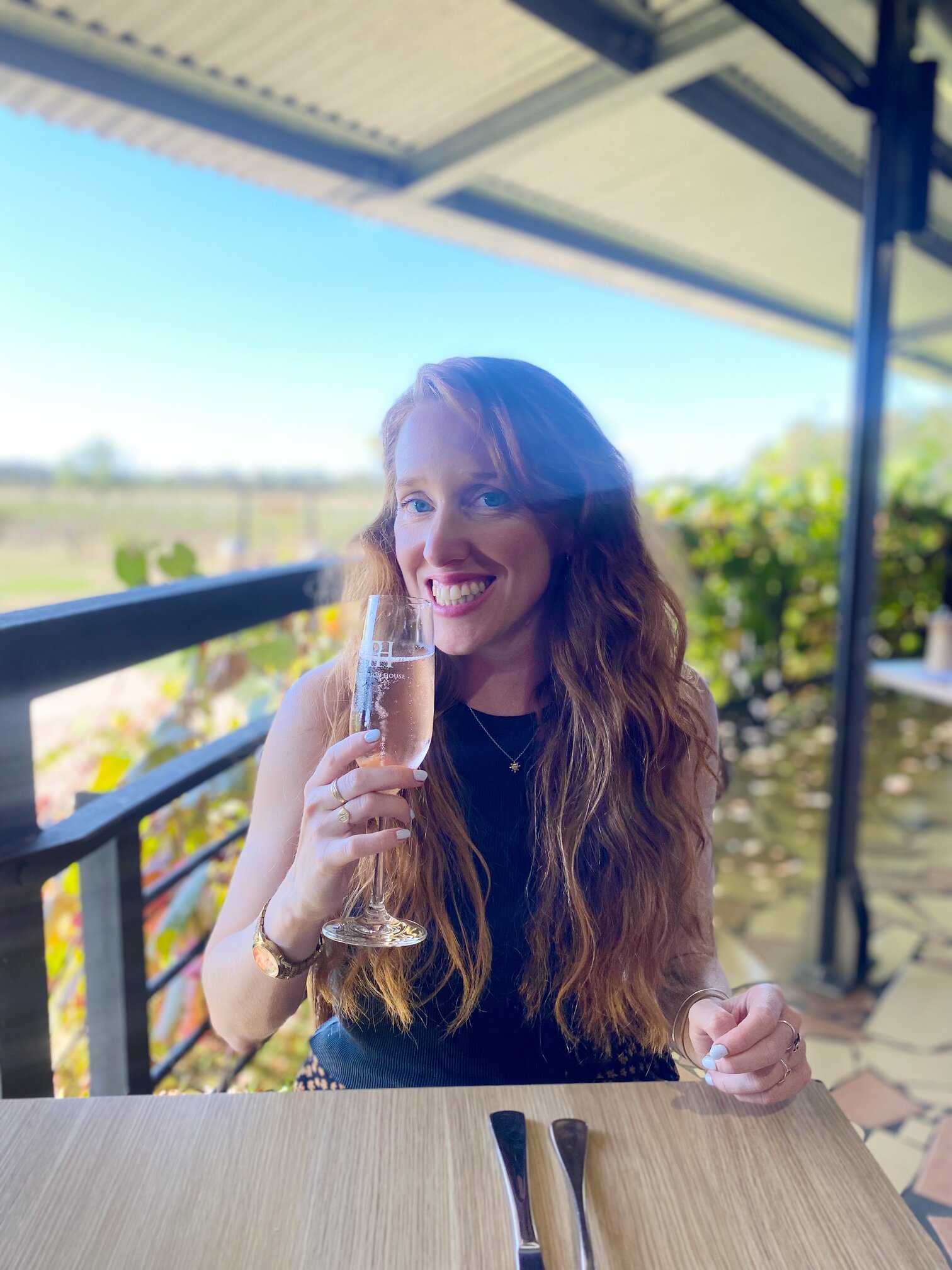 Woman with long wavy hair enjoying wine in a vineyard