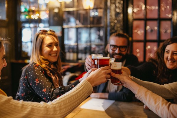 Group of friends toasting with beers at a London pub