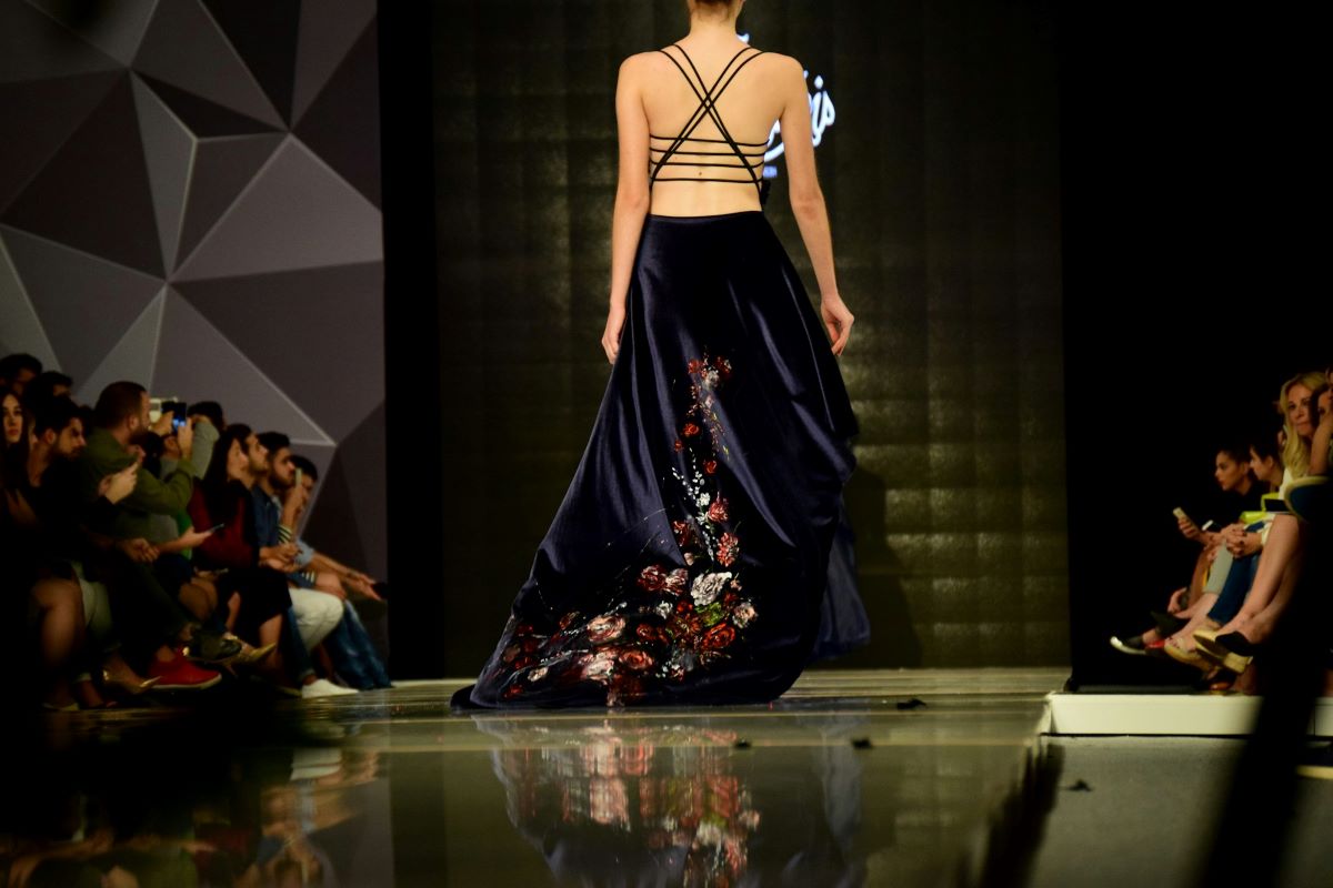 A woman walking down a runway in a dress during fashion week in Lisbon. 