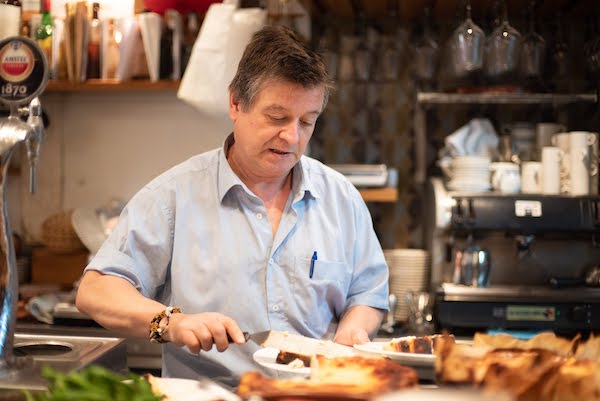 Santiago Rivera, owner of La Viña bar, plating cheesecake