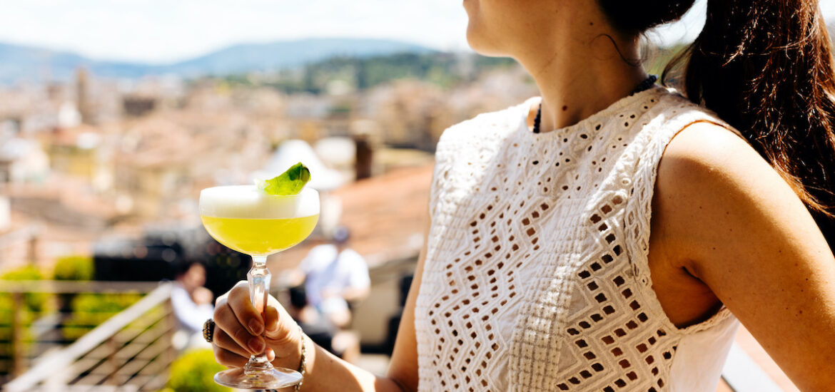 Woman holding a margarita at a rooftop bar overlooking Florence, Italy