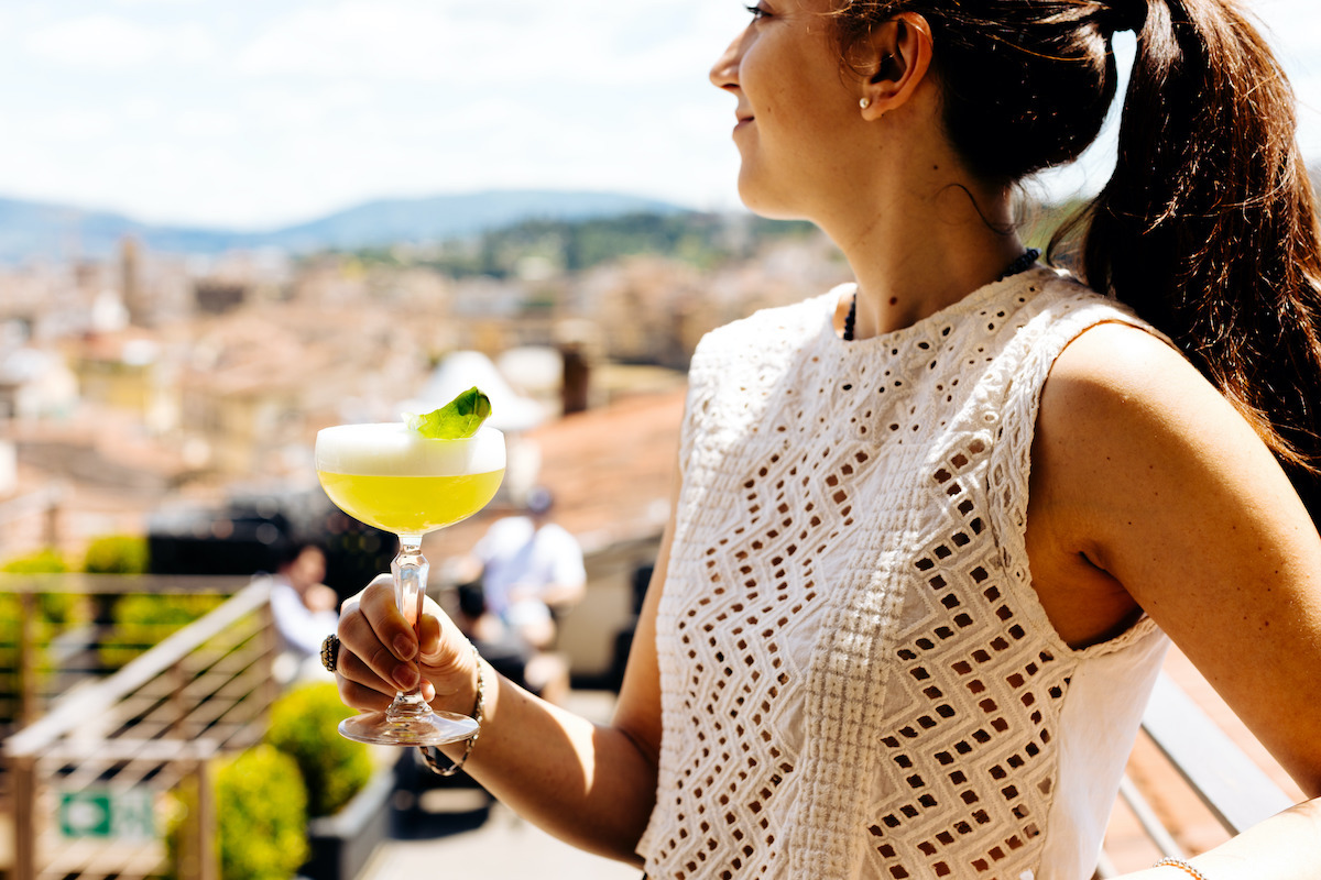 Woman holding a margarita at a rooftop bar overlooking Florence, Italy