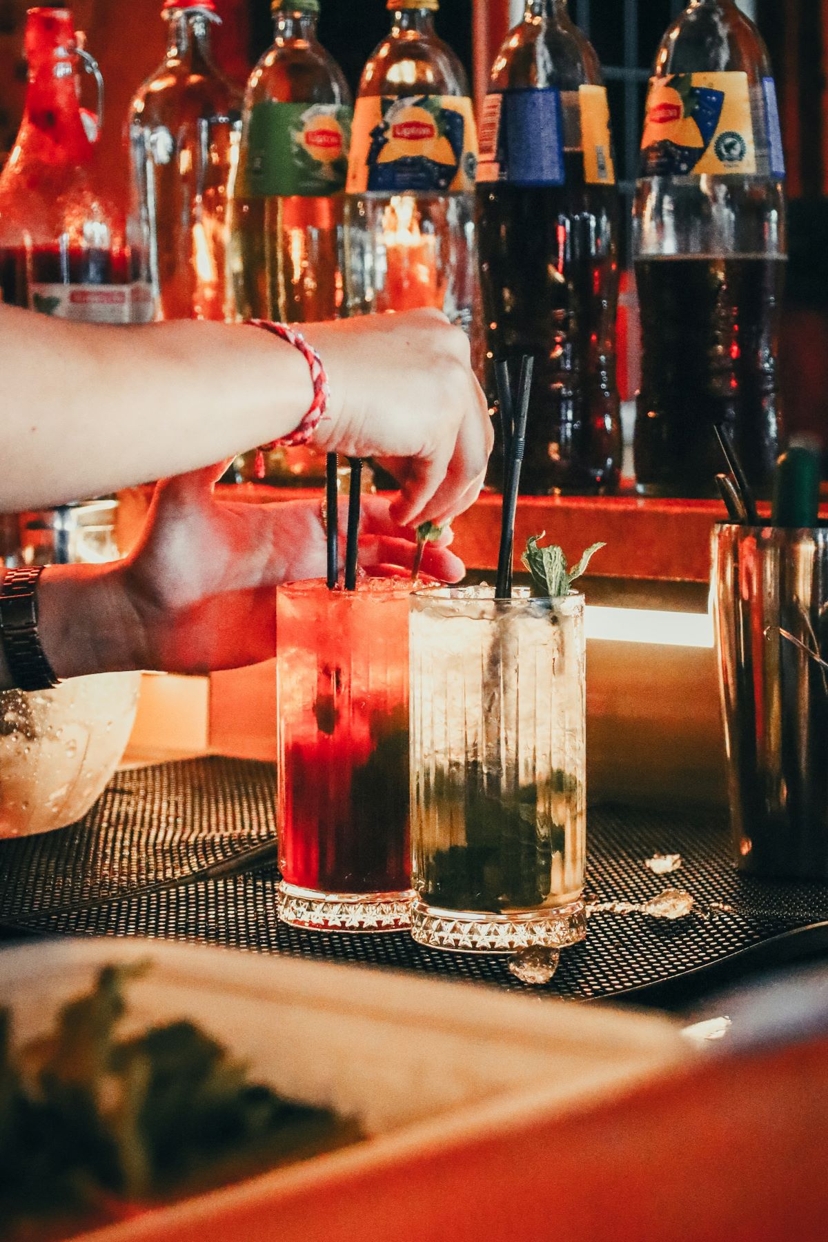 A bartender making two cocktails for bar goers in Bordeaux.