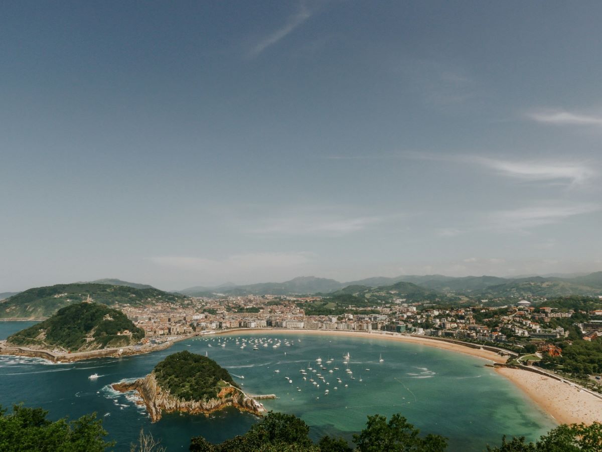 View of La Concha beach with people looking for where to eat near Hotel de Londres in San Sebastian.