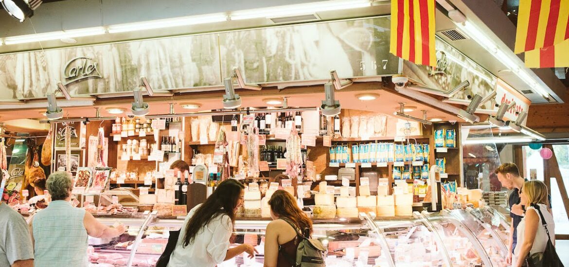 Two women shopping at a cheese stall inside a Spanish food market