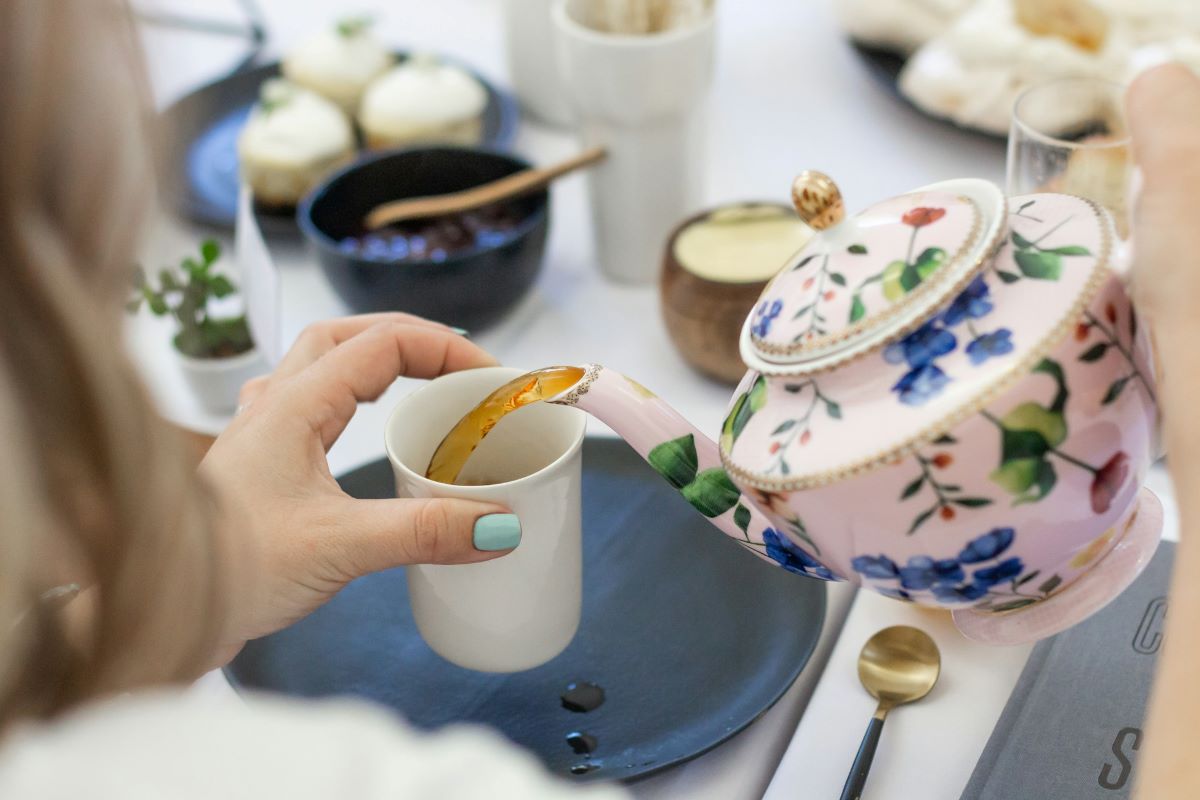 A woman pouring herself a cup of tea in Portugal. Teatime traditions is one of the Portuguese food facts which originated from a Portuguese princess. 