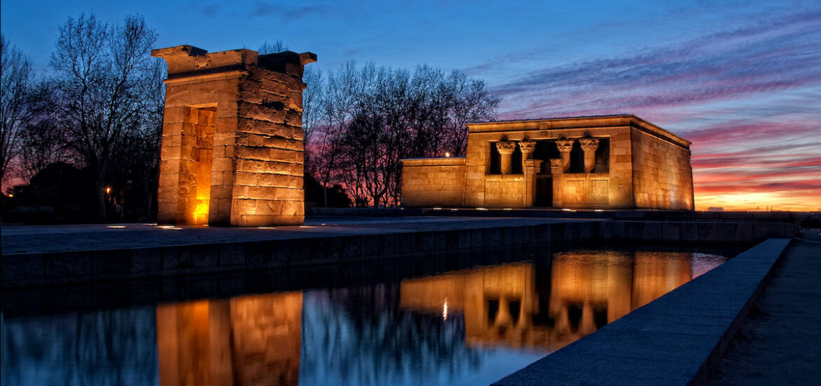 Stone temple located near a small body of water at sunset