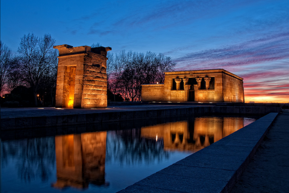 Stone temple located near a small body of water at sunset