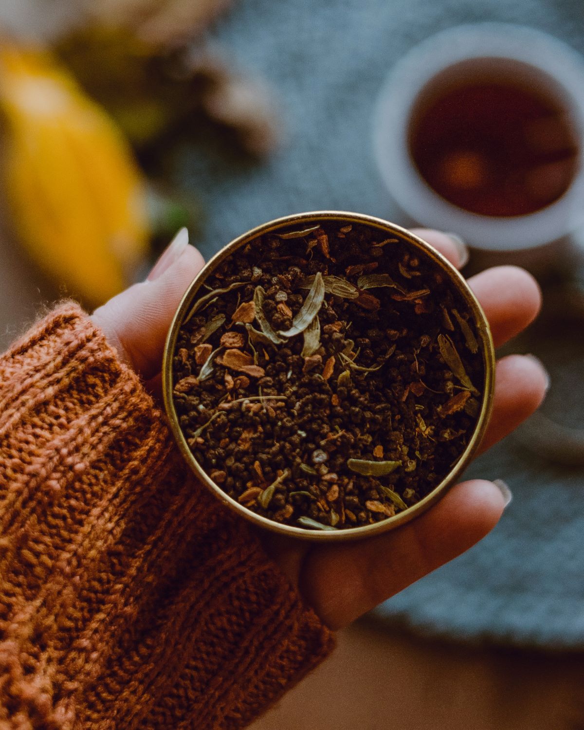 A woman holding a tin with loose leaf tea inside. 