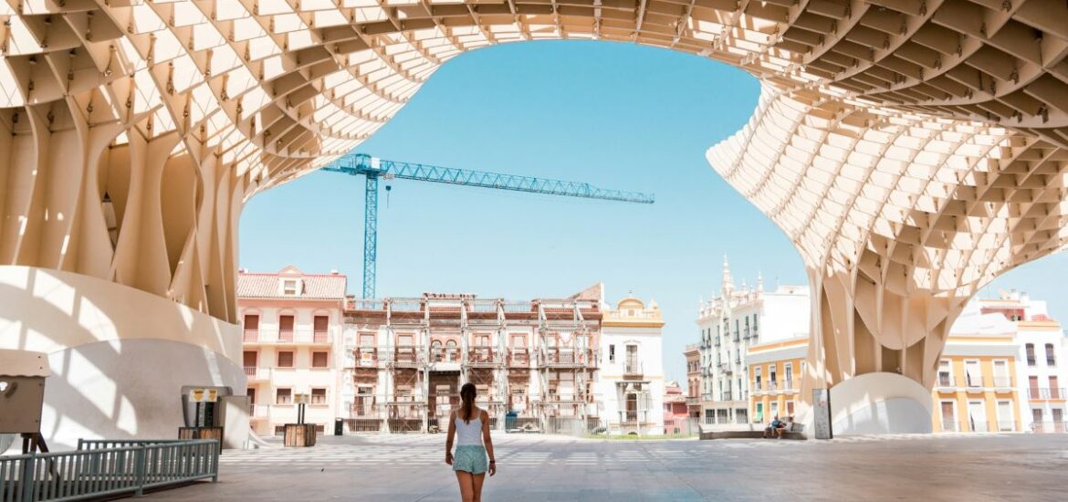 A woman walking underneath the Setas looking for where to cool off in Seville.