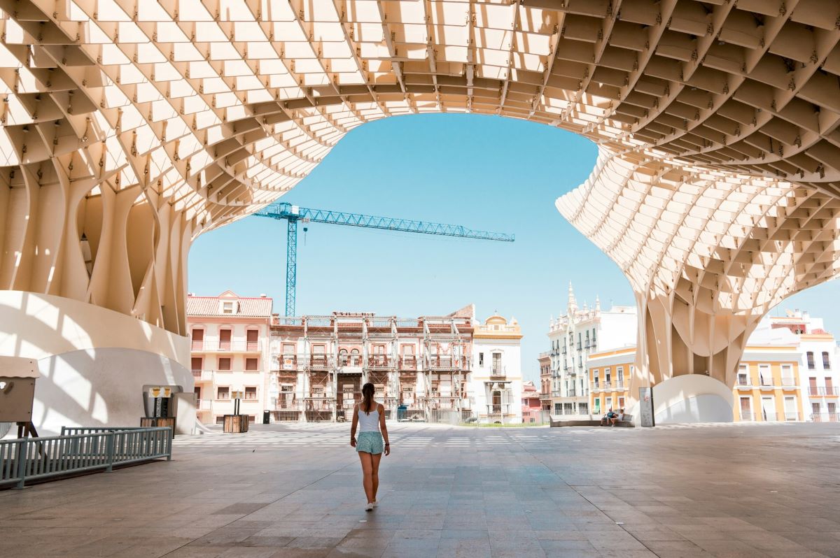 A woman walking underneath the Setas looking for where to cool off in Seville.