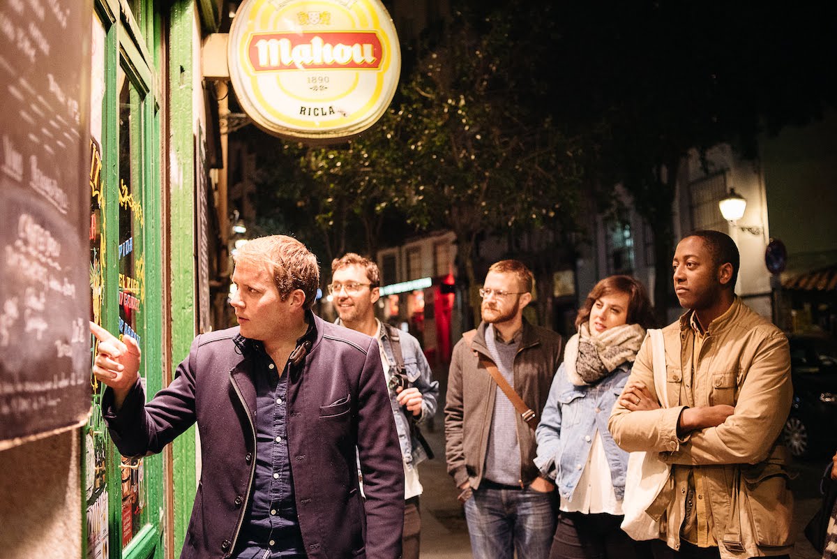 Group of people in winter clothing standing outside a restaurant.