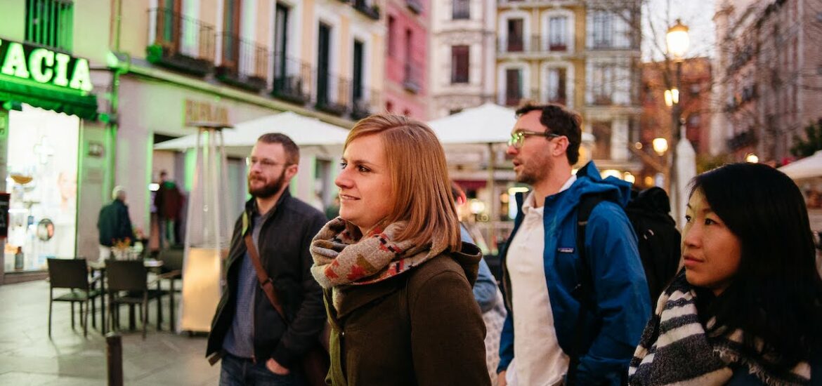 Group of people in winter clothes standing in a city plaza.