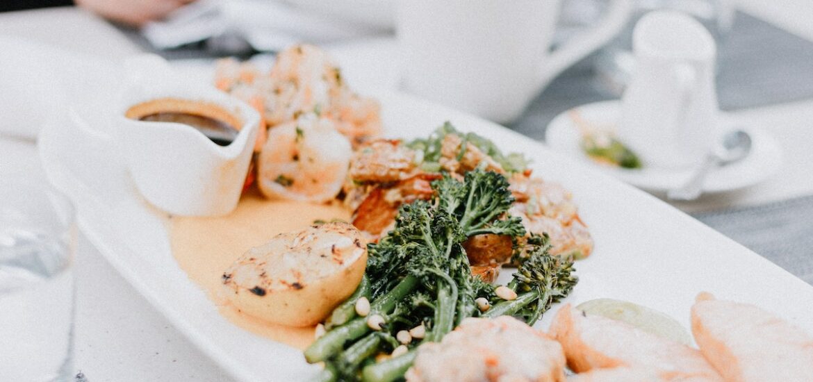 Modern presentation of meat and green vegetables in sauce on an oblong white plate