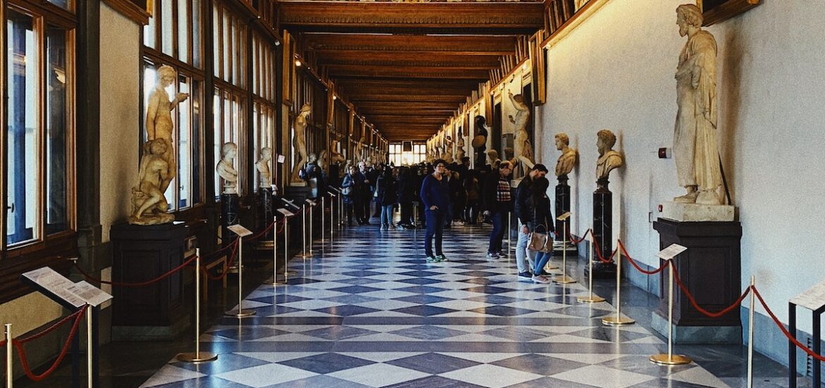 Long hallway of the Uffizi Museum in Florence with black and white checkered floors lined by marble statues