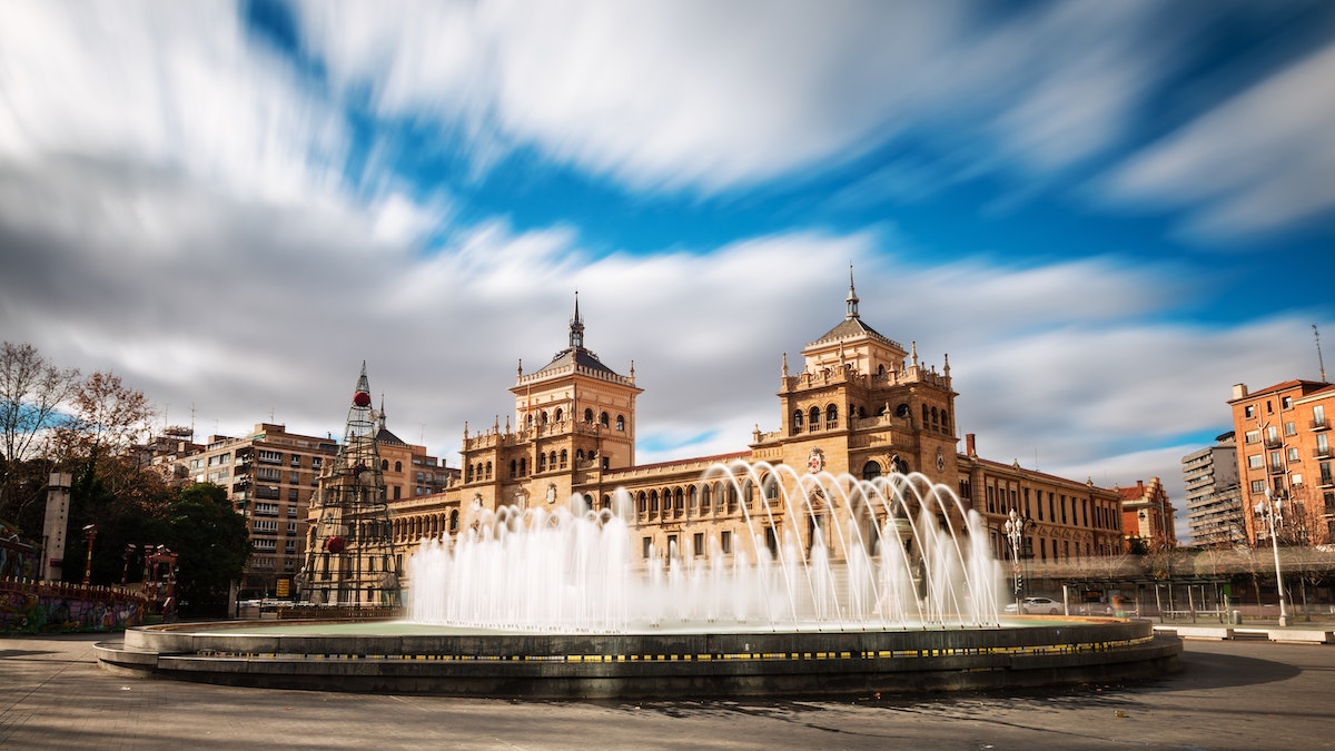 Large fountain in a plaza in front of a huge building