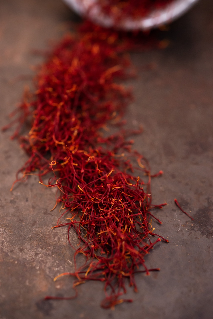 Vertical photo of red saffron spilling out of a jar