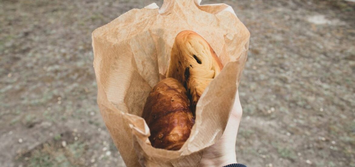 A person holding a paper bag with pastries from the best bakeries in Bordeaux.