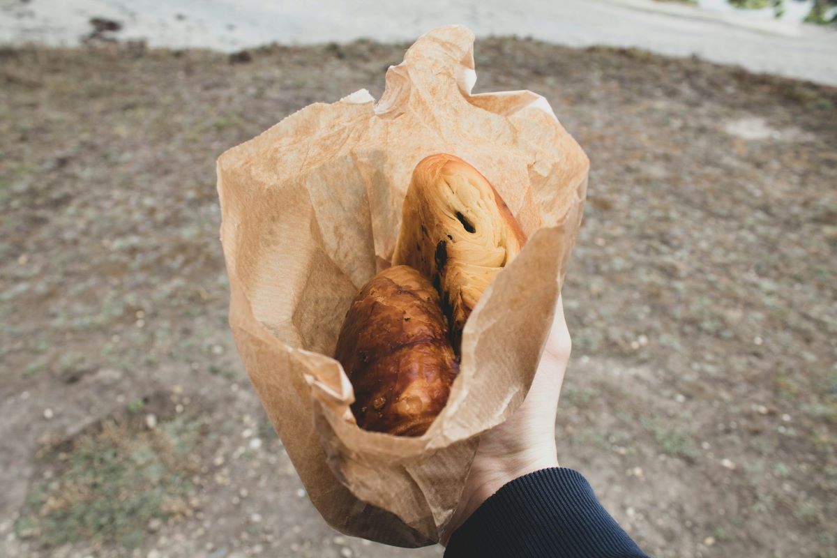A person holding a paper bag with pastries from the best bakeries in Bordeaux.