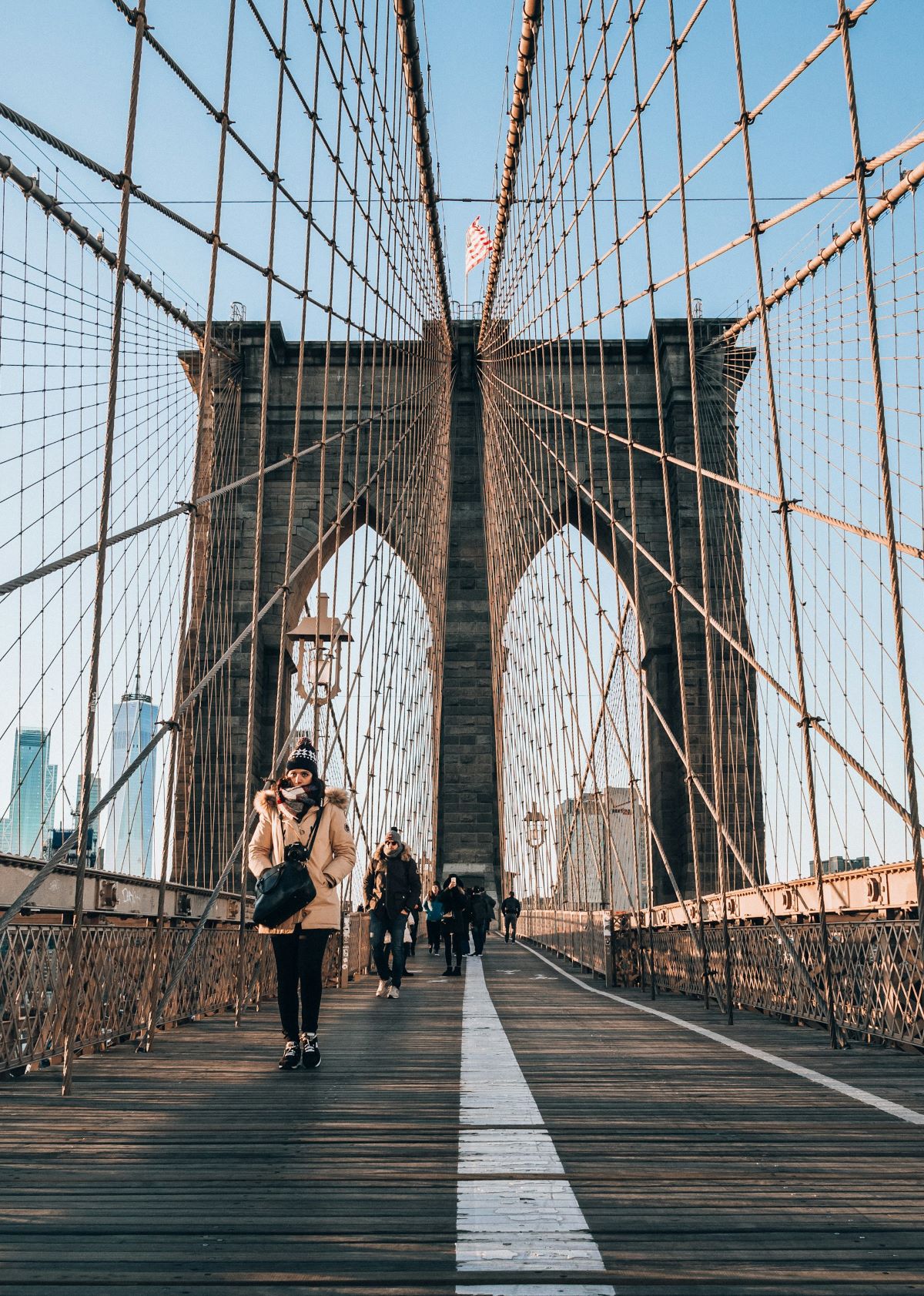 People walking on the Brooklyn Bridge searching for hidden gems to visit around New York. 